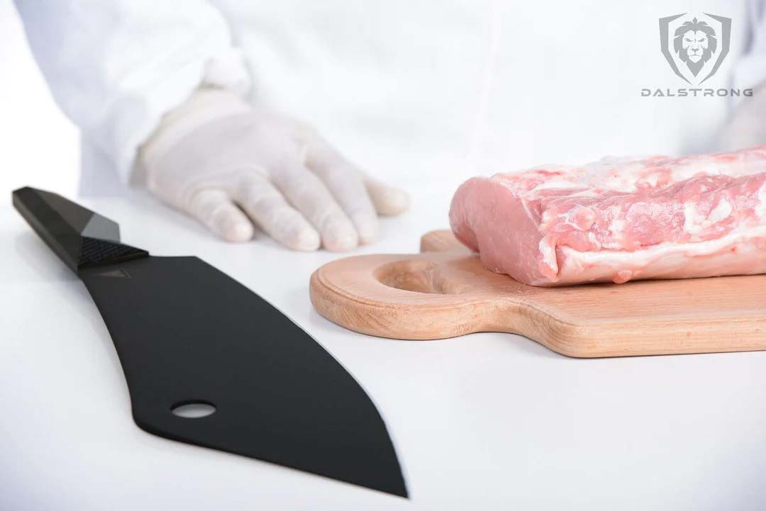 Dalstrong shadow black series 8 inch crixus cleaver knife with a large cut of meat on a cutting board.