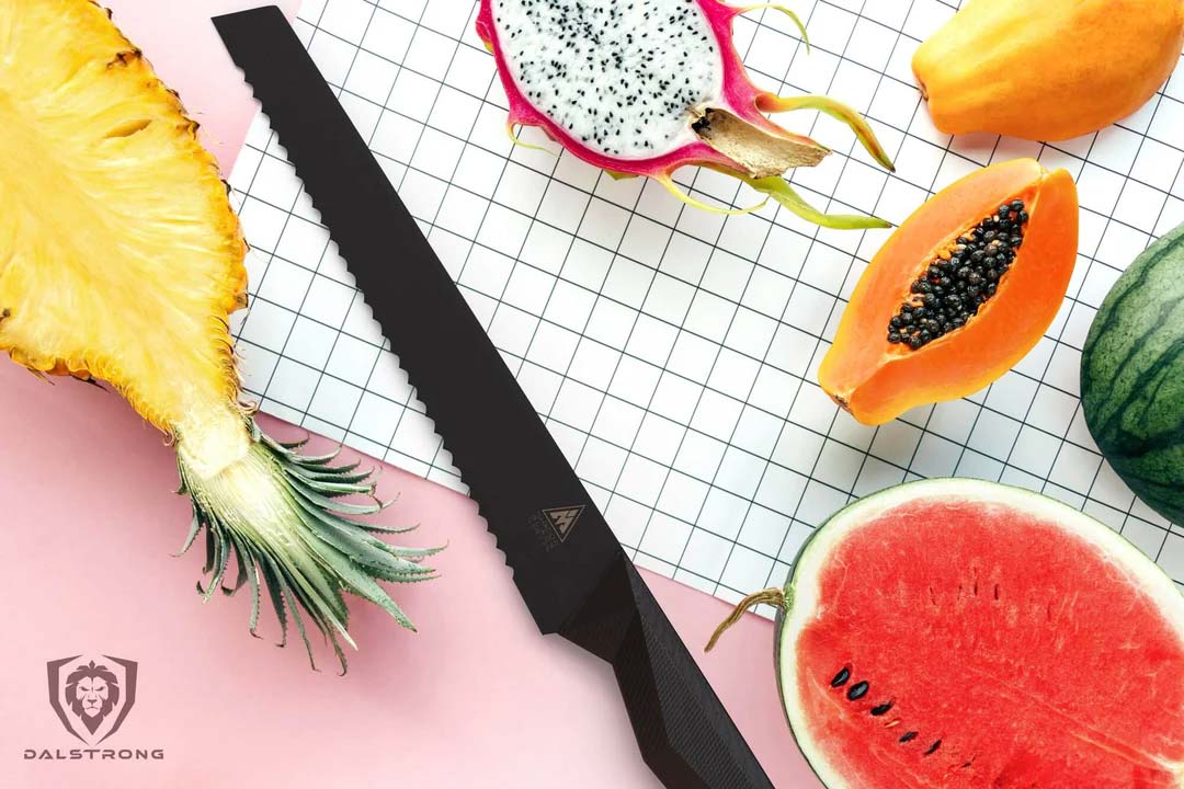 Dalstrong shadow black series 9 inch bread knife with four different fruits surrounding it.