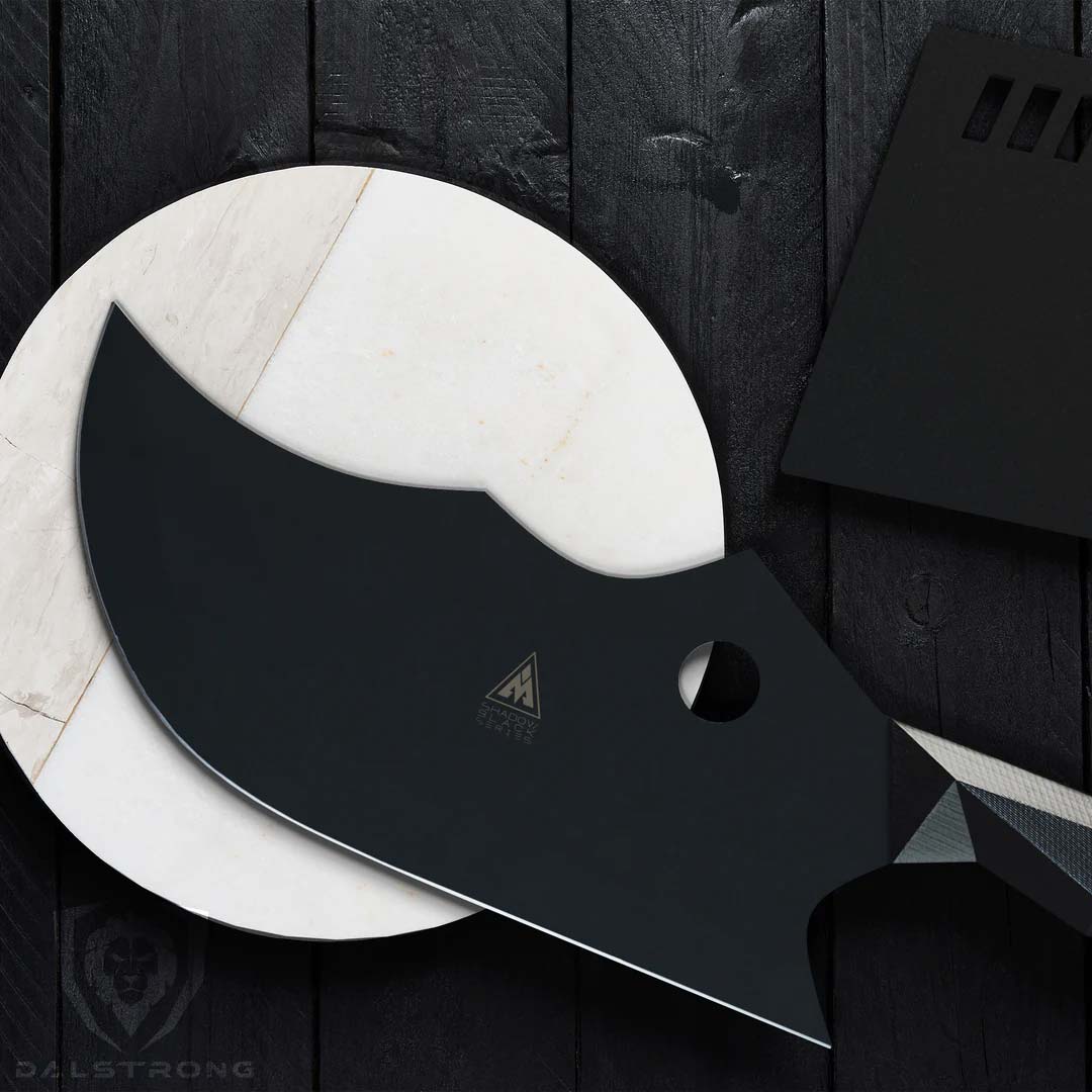 Dalstrong shadow black series 9 inch cleaver knife on top of a wooden white board beside it's black sheath.