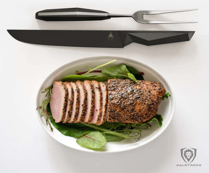 Dalstrong shadow black series 9 inch carving and fork set with slices of pork loin.