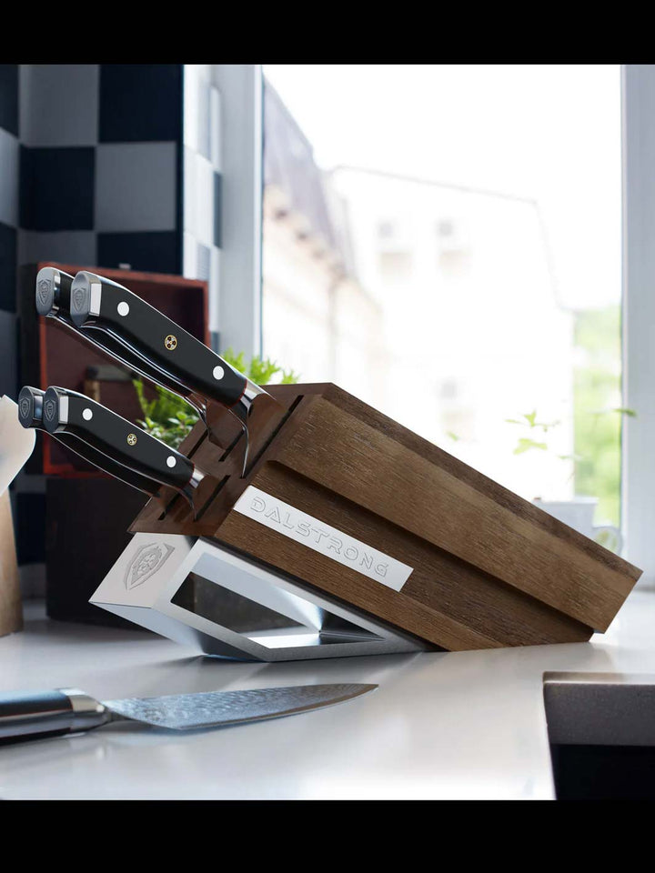 Dalstrong shogun series 5 piece knife set with block and black handles on top of a kitchen table.