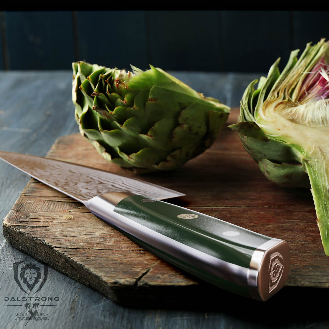Dalstrong shogun series 8 inch chef knife with army green handle and artichoke on a wooden board.