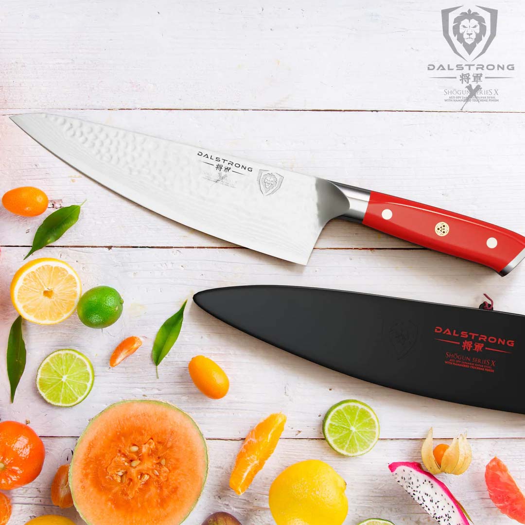 Dalstrong shogun series 8 inch chef knife with crimson red handle and sheath on top of different slices of fruits.
