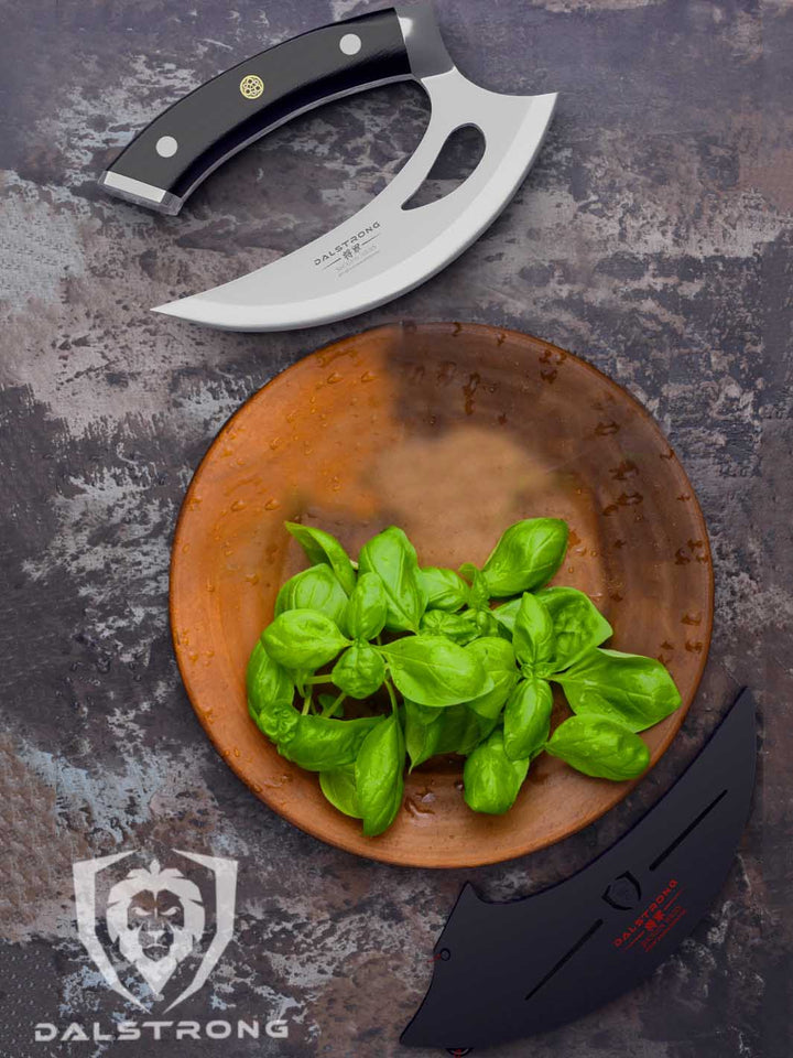 Dalstrong shogun series 6 inch ulu knife with black handle and basil leaves in the middle.