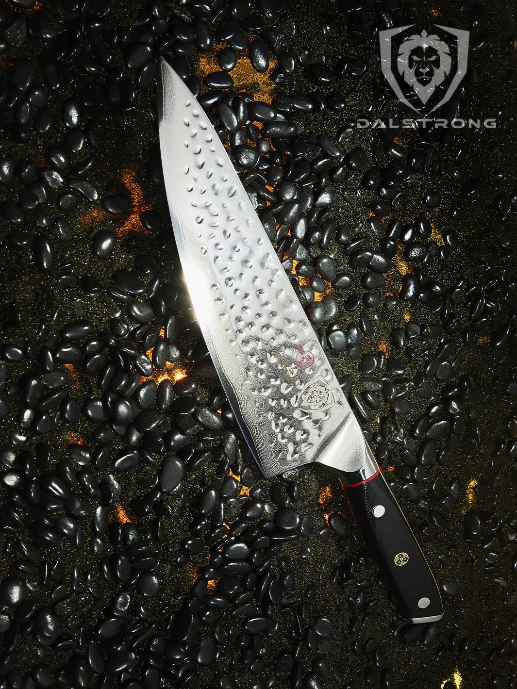 Dalstrong 8 inch chef knife with black in a black sand with black pebbles.