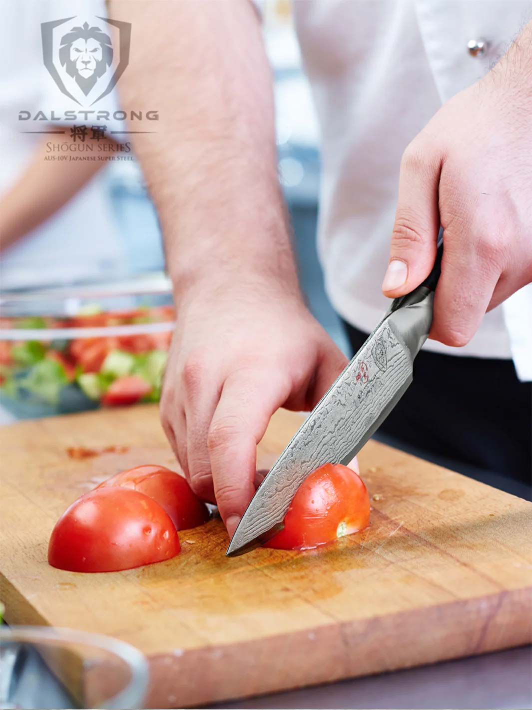 Dalstrong shogun series 6 inch utility knife with black handle slicing through a tomato on a wooden board.
