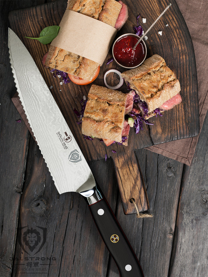 Dalstrong shogun series 7.5 inch serrated chef knife with a sandwich cut in three on a wooden board.