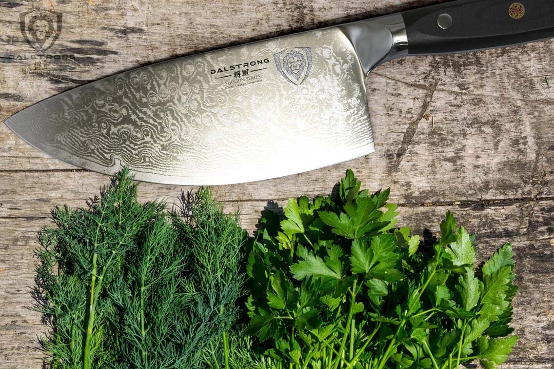 Dalstrong shogun series 7 inch rocker cleaver knife with black handle on top of two kinds of herbs.