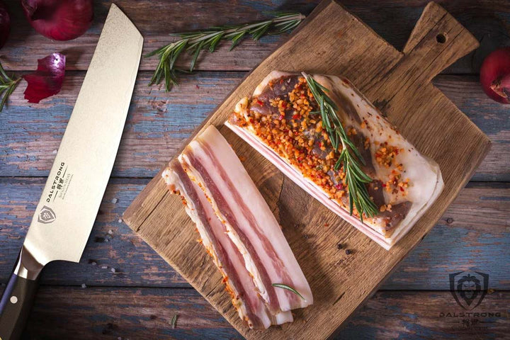 Dalstrong shogun series 8 inch tanto chef knife with a sliced meat on a wooden board.