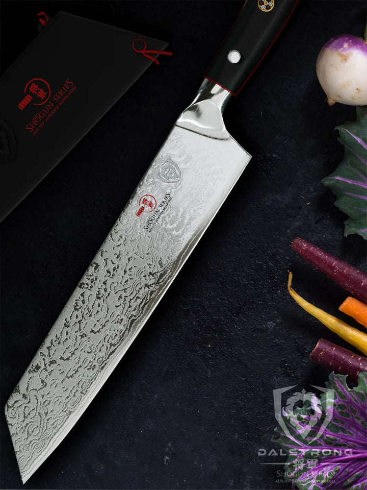 Dalstrong shogun series 8.5 inch kiritsuke knife with black handle and different kinds of vegetables on the side.
