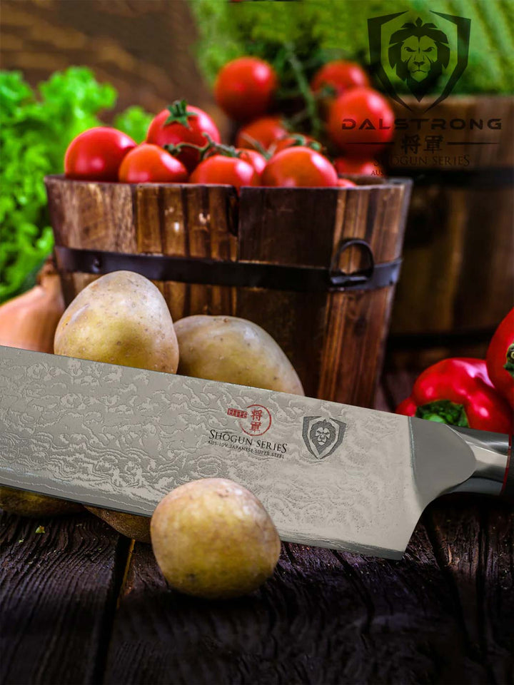 Dalstrong shogun series 8.5 inch kiritsuke knife with potatoes and tomatoes inside of a box.