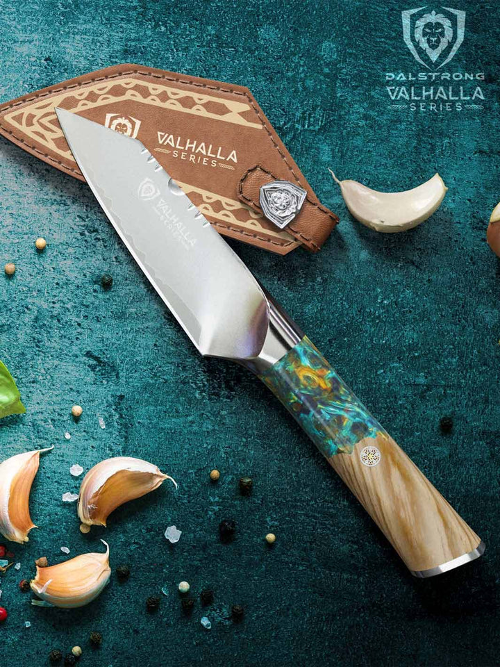 Dalstrong valhalla series 4 inch paring knife with wooden handle beside some garlic.