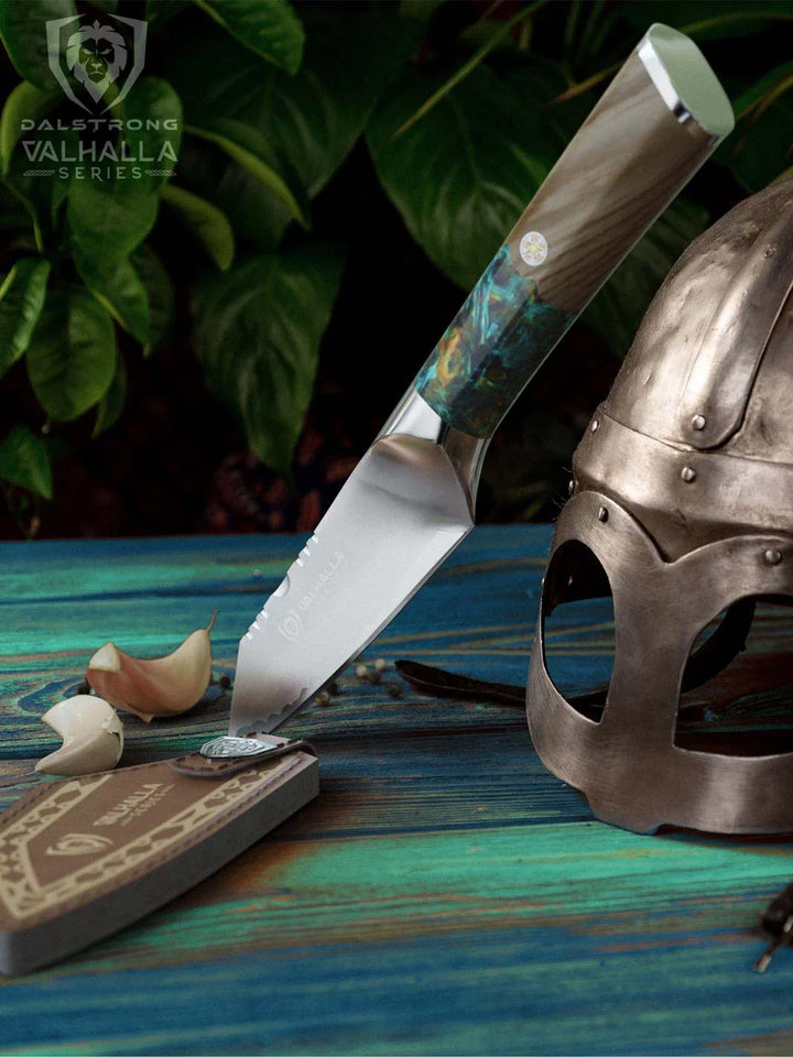 Dalstrong valhalla series 4 inch paring knife with wooden handle beside a viking helmet.
