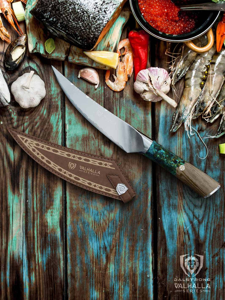 Dalstrong valhalla series 6.5 inch fillet knife with wooden handle and sheath beside a sliced fish and shrimps.