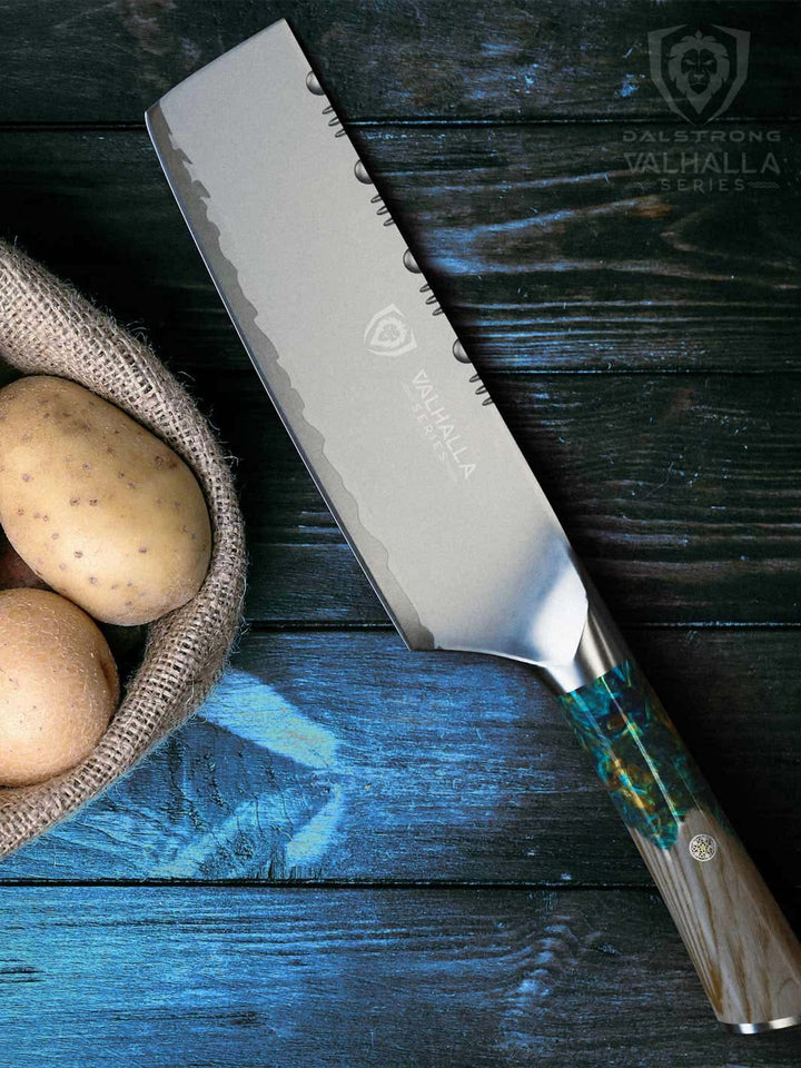Dalstrong valhalla series 7 inch nakiri knife with wooden handle and potatoes inside a basket.