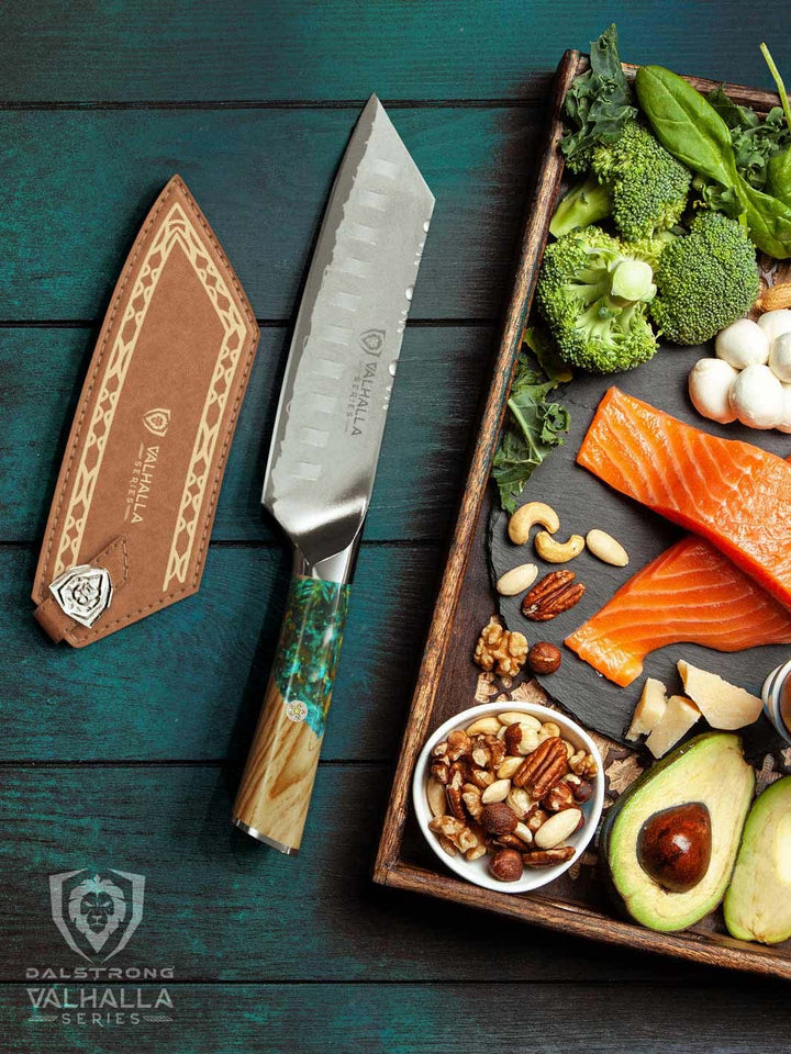 Dalstrong valhalla series 7 inch santoku knife with wooden handle and sheath beside two fillets of fish and vegetables.