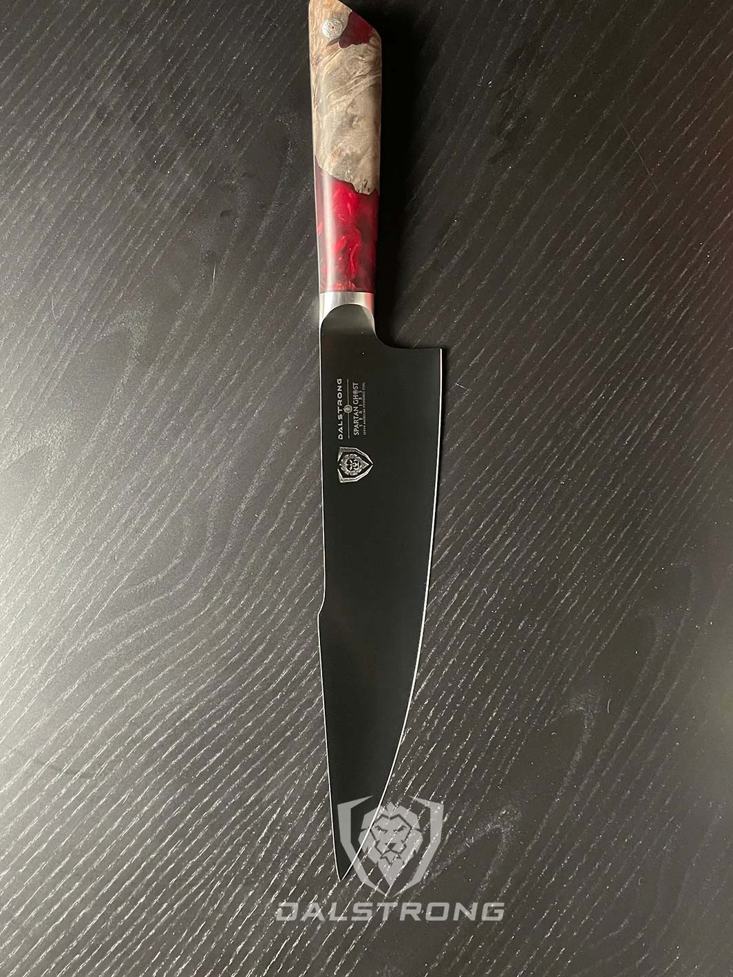 Dalstrong spartan ghost series 9.5 inch chef knife with resin and ash wood handle in a table.