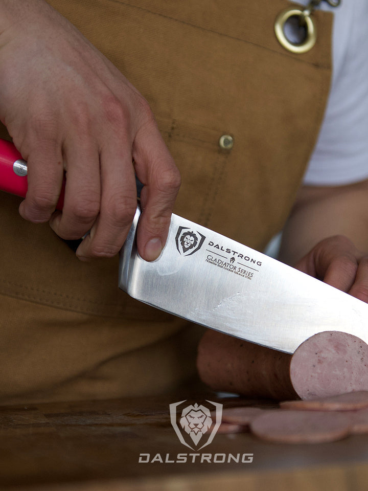 Dalstrong gladiator series 8 inch chef knife with fushia handle slicing through a sausage.