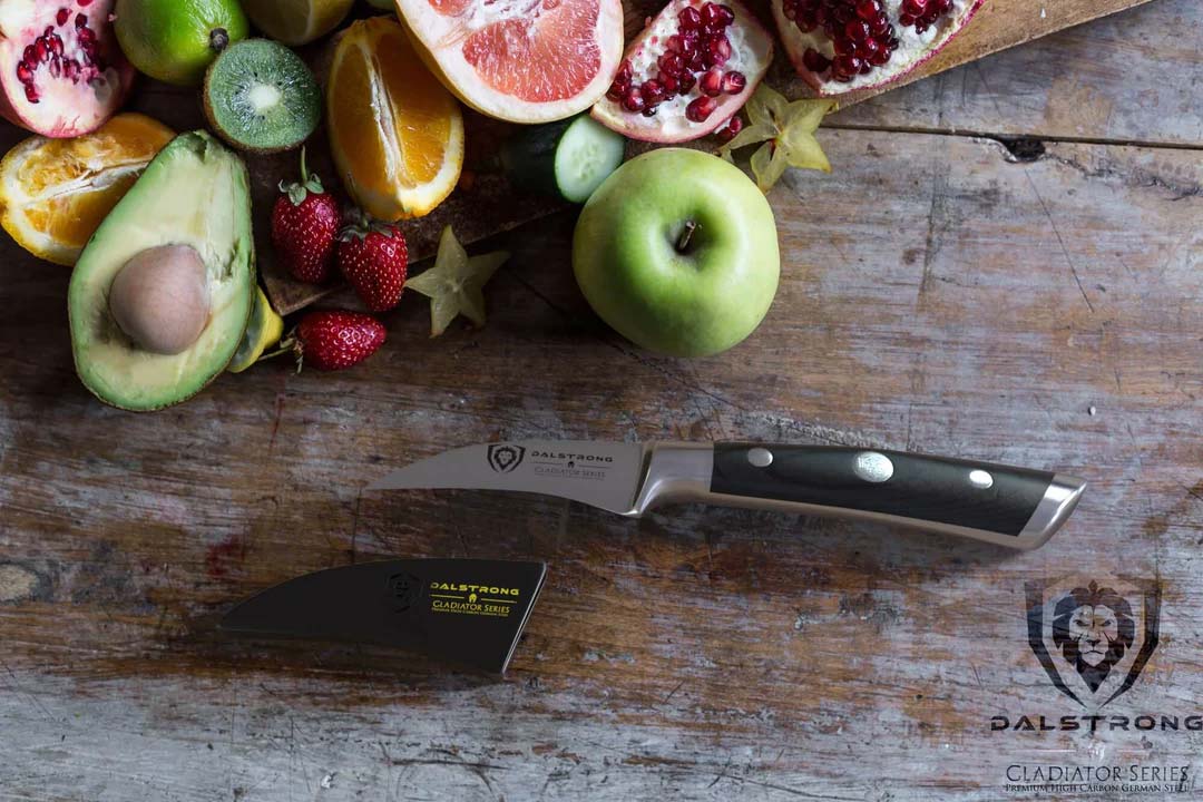 Dalstrong gladiator series 2.7 inch bird's beak paring knife with black handle and different kinds of fruits.