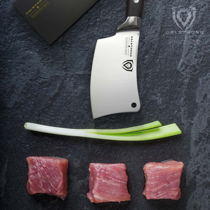 Dalstrong gladiator series 4.5 inch mini cleaver knife with black handle and small cuts of meat below it.