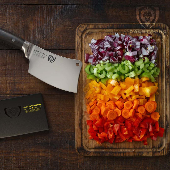 Dalstrong gladiator series 4.5 inch mini cleaver knife with black handle and small cuts of vegetables on a wooden board.