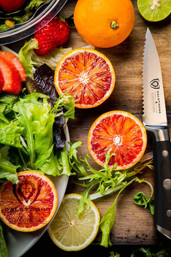 Dalstrong gladiator series 3.75 inch serrated paring knife with black handle and oranges beside it.