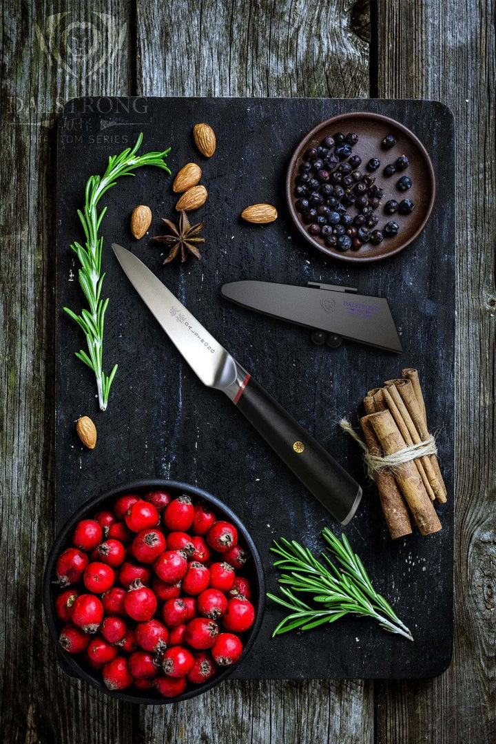 Dalstrong phantom series 4 inch paring knife with pakka wood handle surrounded by herbs on a cutting board.