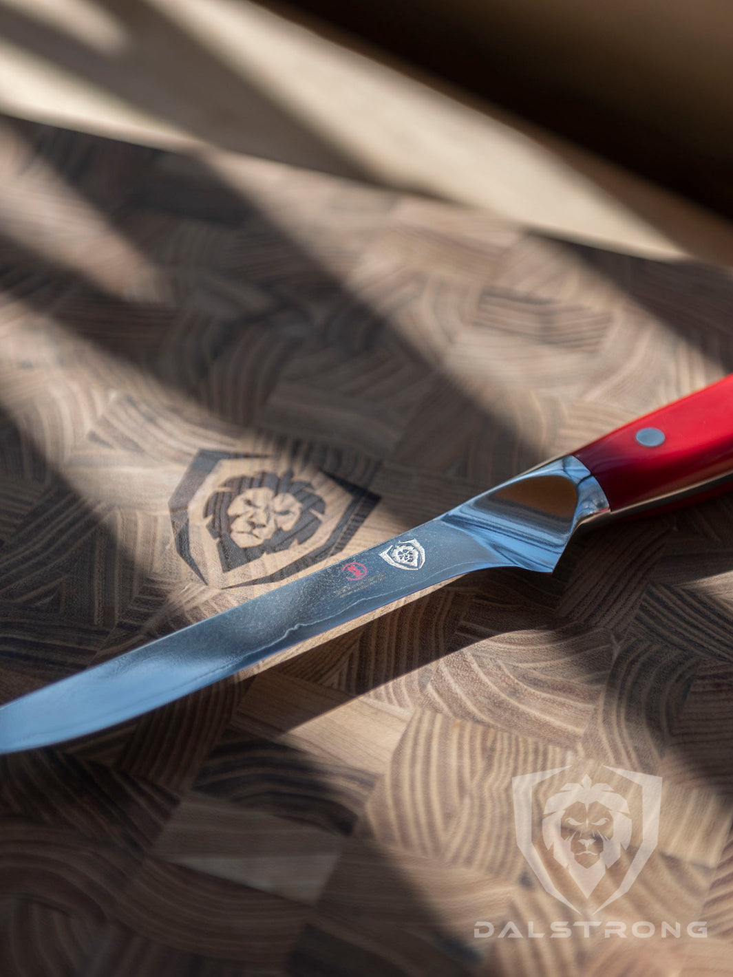 Dalstrong shogun series 6 inch boning knife with red handle in top of a dalstrong wooden board.
