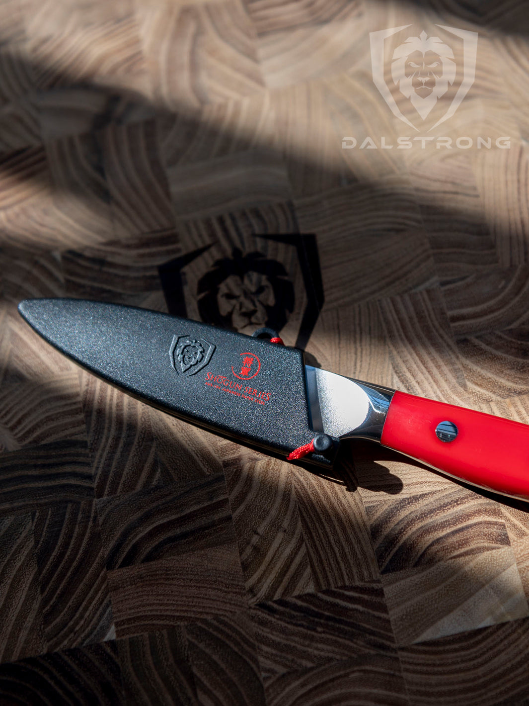 Dalstrong shogun series 3.5 inch paring knife with crimson red handle inside of it's black sheath on top of a dalstrong wooden board.