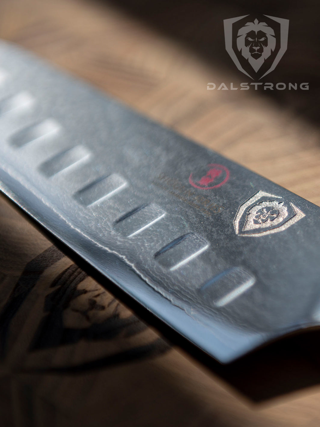 Dalstrong shogun series 7 inch santoku knife with crimson red handle and dalstrong logo shined directly by the light.