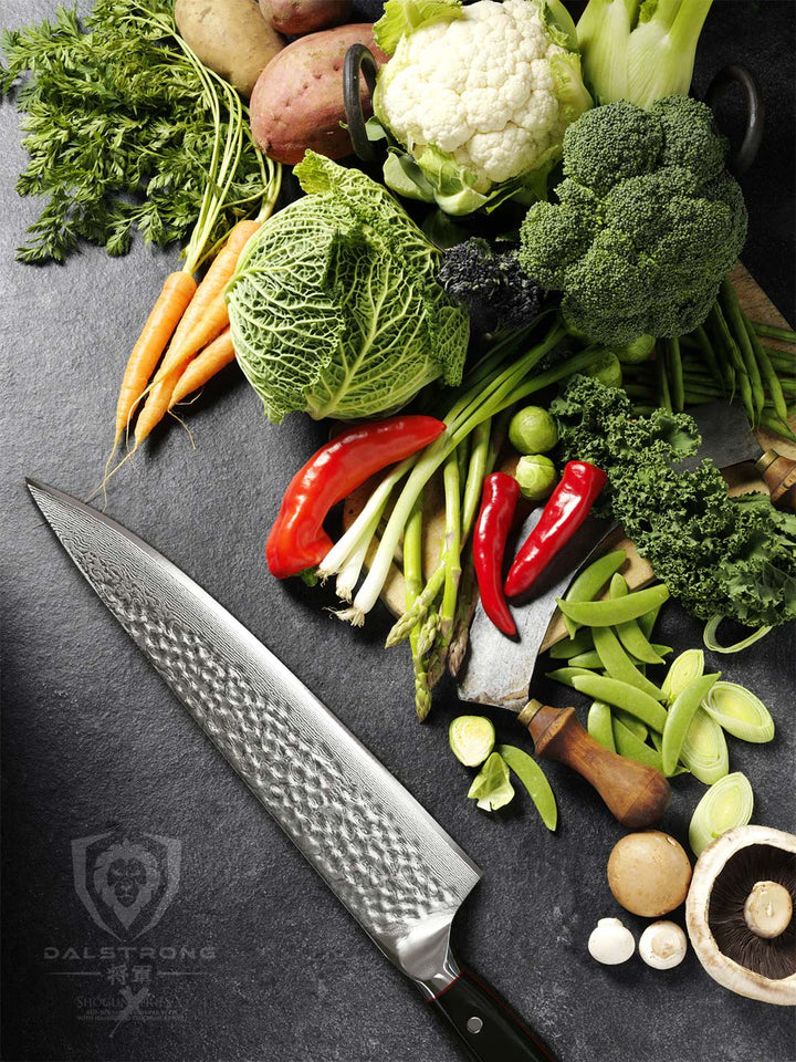Dalstrong shogun series 10.25 inch chef knife with black handle and different kinds of vegetables at the side.