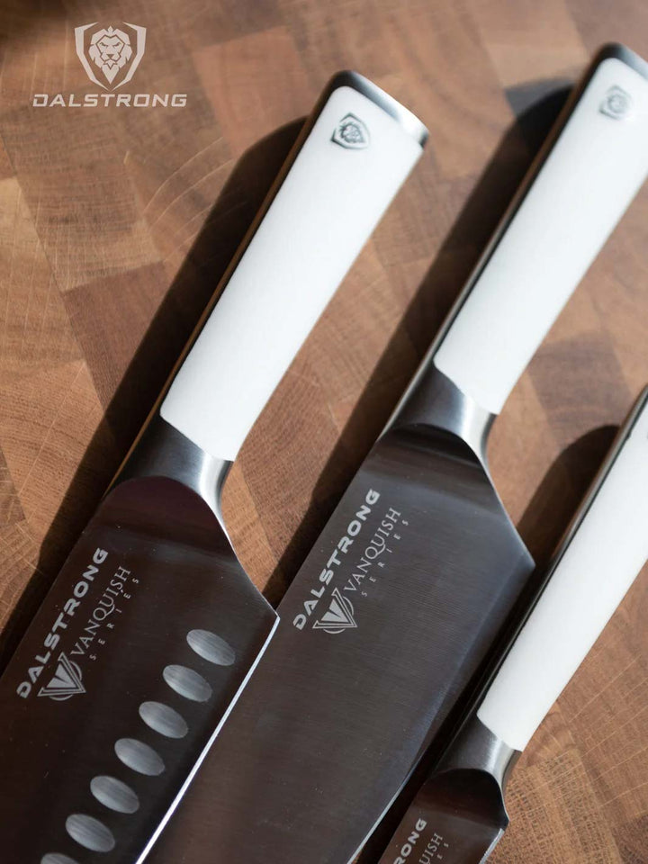 Dalstrong vanquish series 3 piece knife set with white handles on a cutting board.