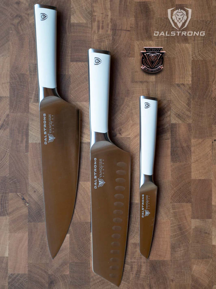 Dalstrong vanquish series 3 piece knife set with white handles on a wooden cutting board with pin.
