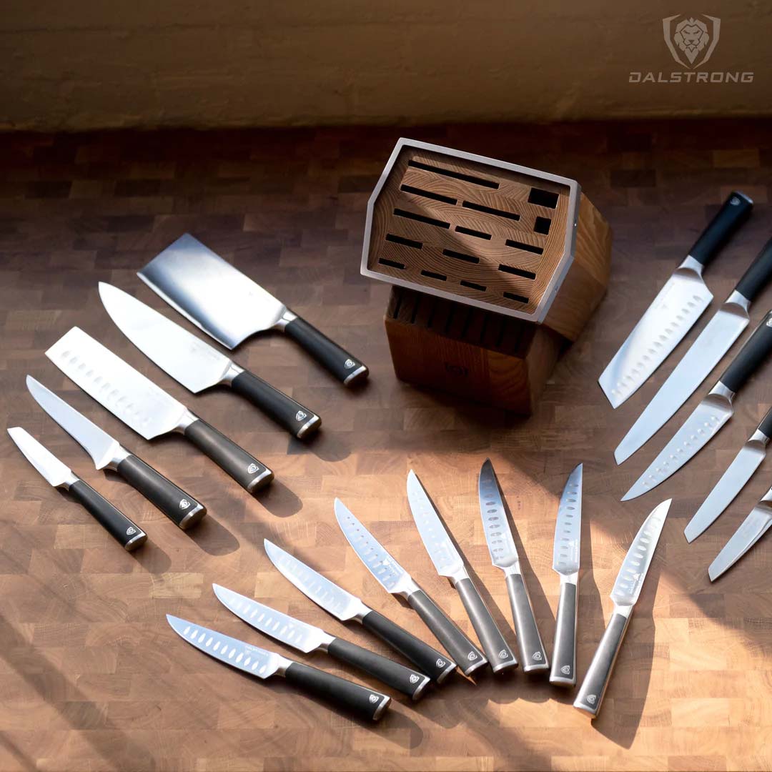 Dalstrong vanquish series 24 piece knife set on a table beside it's wooden block.